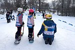 Två små barn testar snowboard med ledare från Alla på snö.