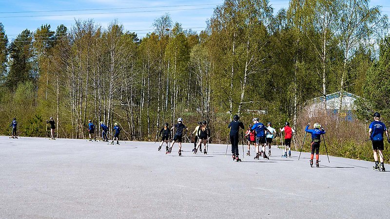 Flertalet ungdomar åker rullskidor på en stor asfaltsyta.
